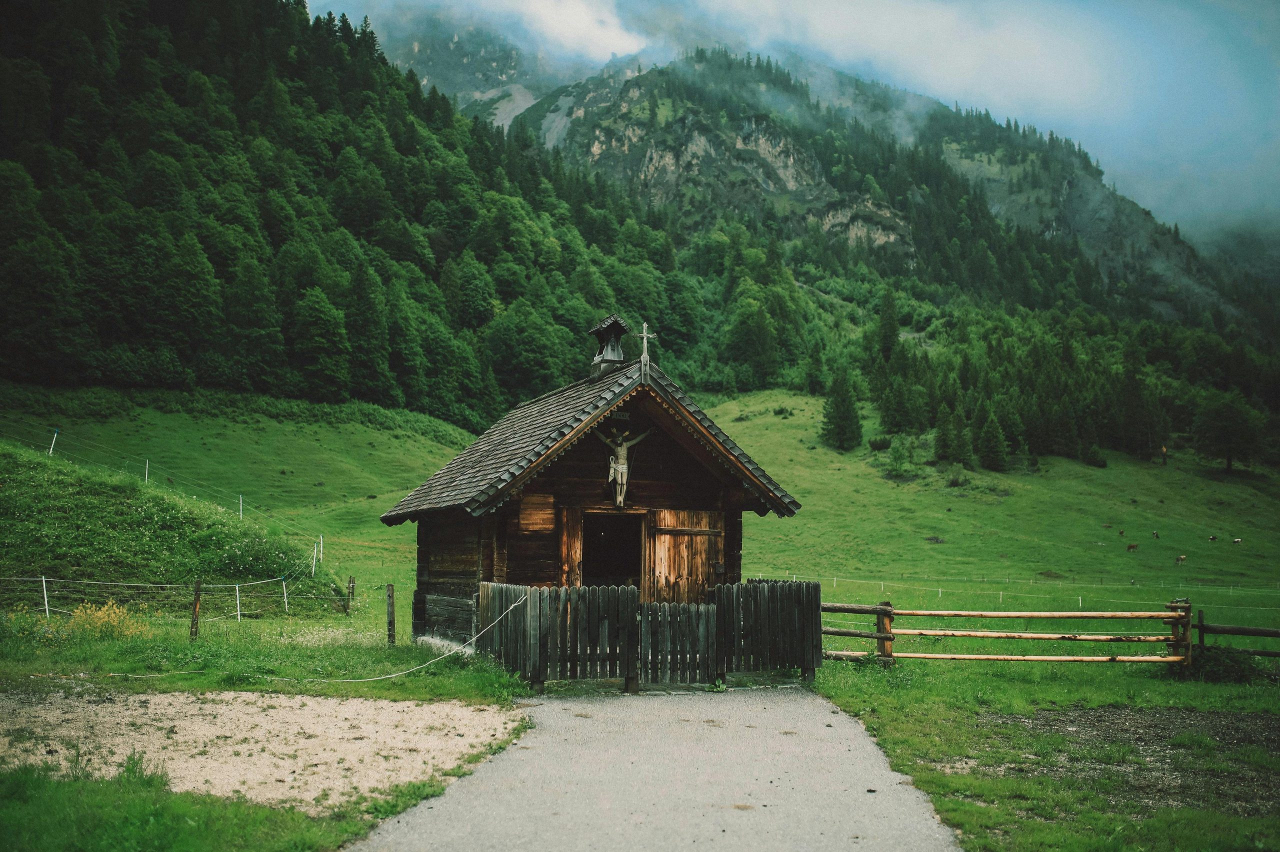 A charming wooden cabin set in a lush green valley beneath misty mountains, showcasing rural serenity.